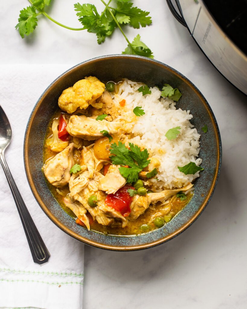 Curried Chicken stew in a bowl with a spoon and napkin beside it.