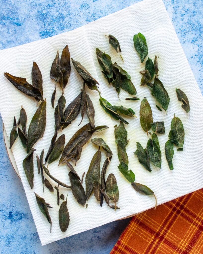 fried sage leaves on a paper towel-lined plate.
