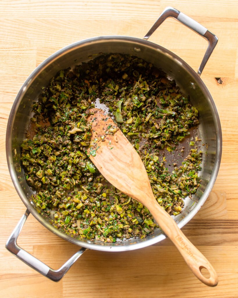 Looking straight down into a sauté pan with cooked leek and mushroom filling.