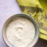 Whipped feta spread in a small bowl with a green kitchen towel.