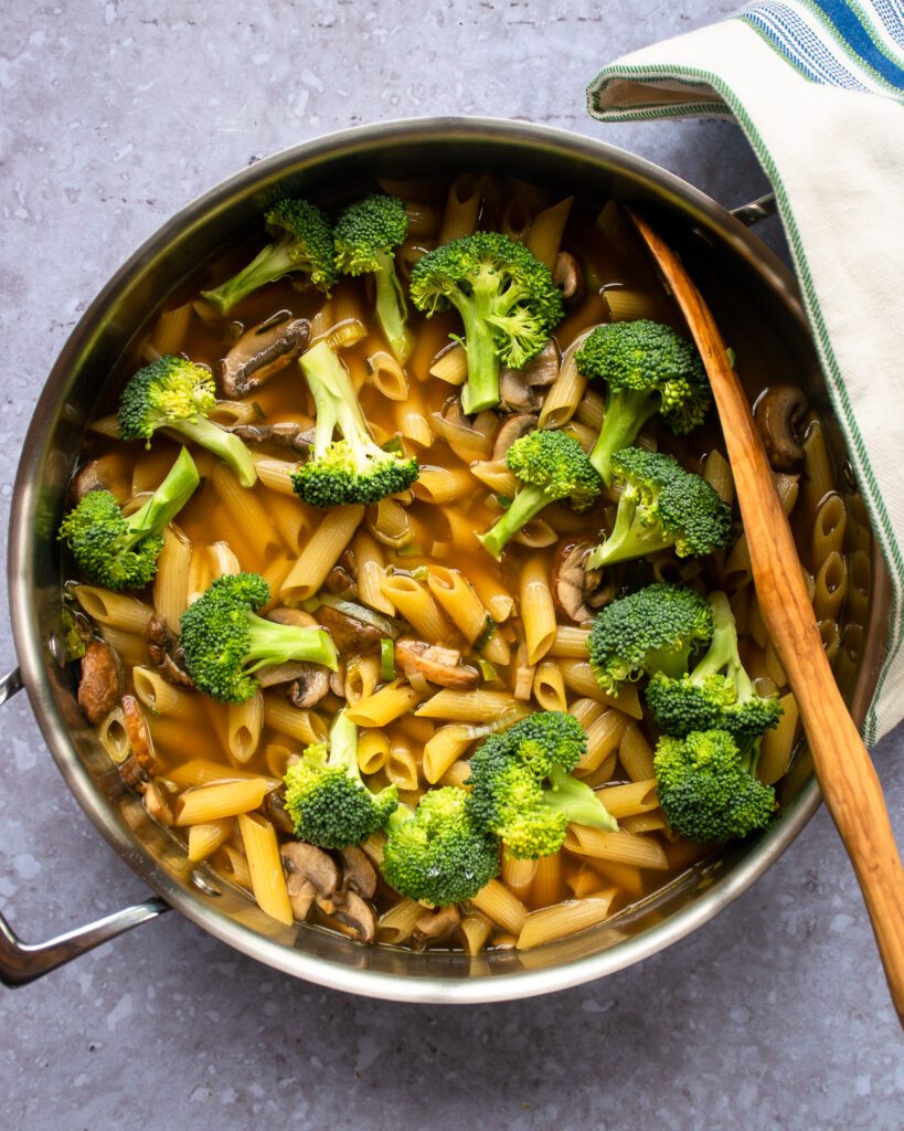 Looking down on a one pot pasta with mushrooms, leeks and broccoli.