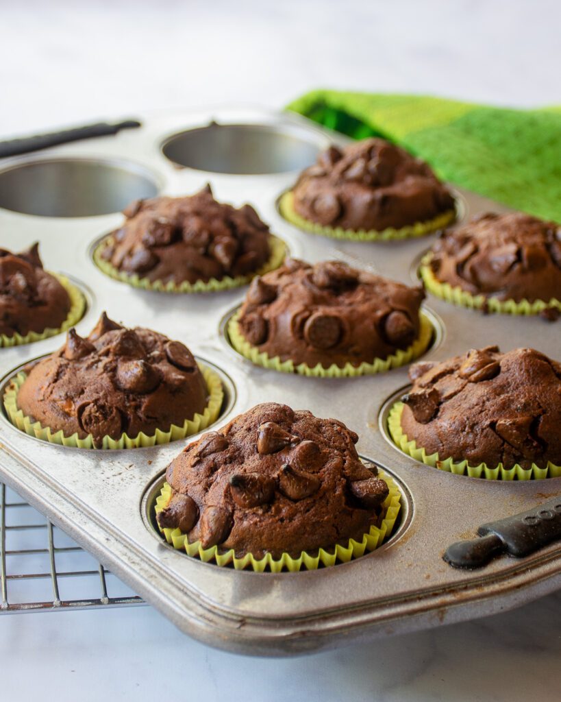 a close up look at chocolate zucchini muffins in a muffin pan.