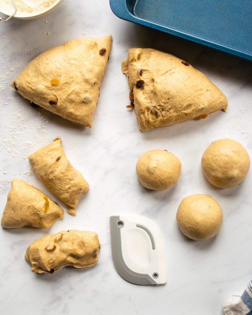 Portions of dough on a counter top - two large chunks, three small chunks and three shaped balls.