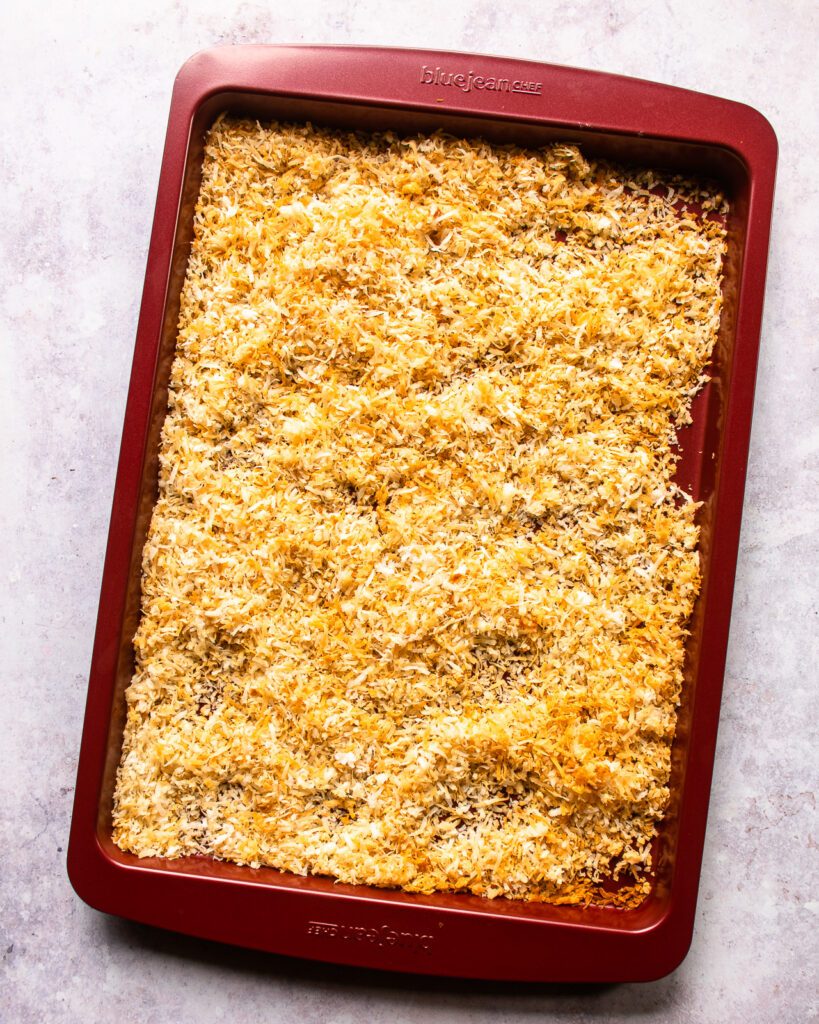 Shredded coconut, toasted on a big red sheet pan.