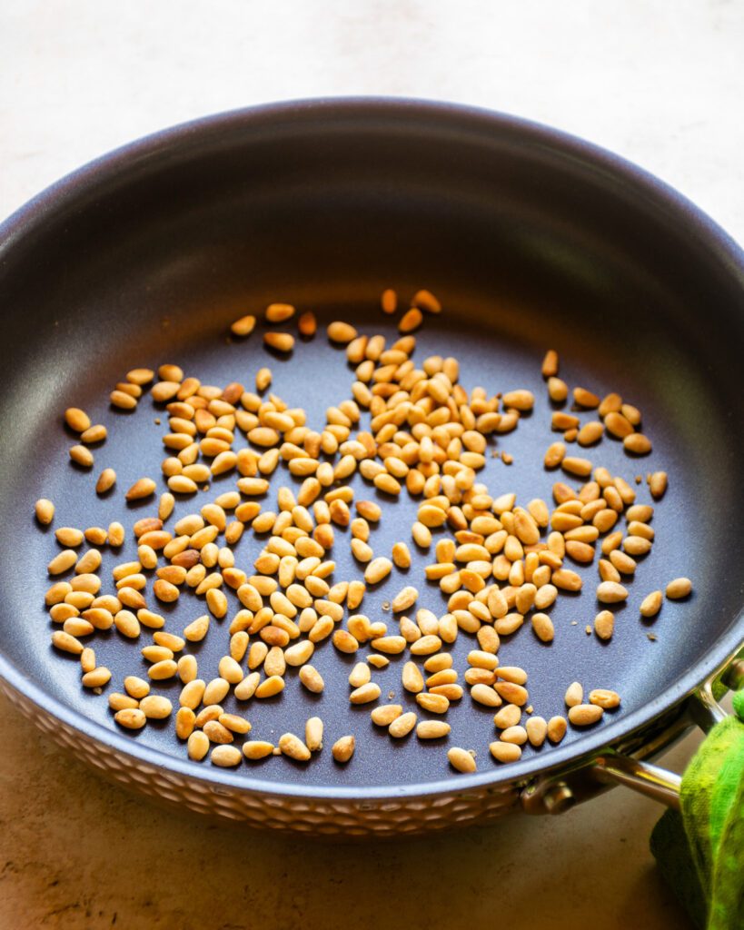 Pinenuts toasting in a non-stick skillet.