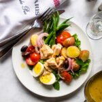 Looking straight down on a dinner plate of Niçoise salad with table setting.