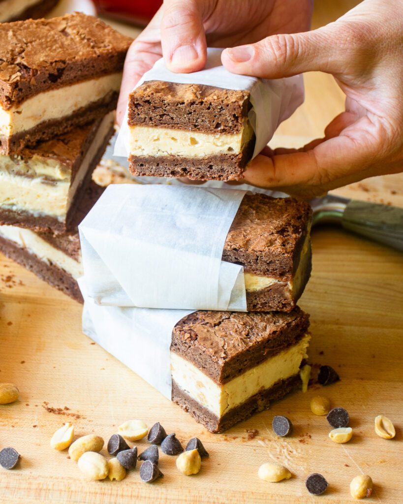 Hands holding a parchment paper wrapped ice cream sandwich.