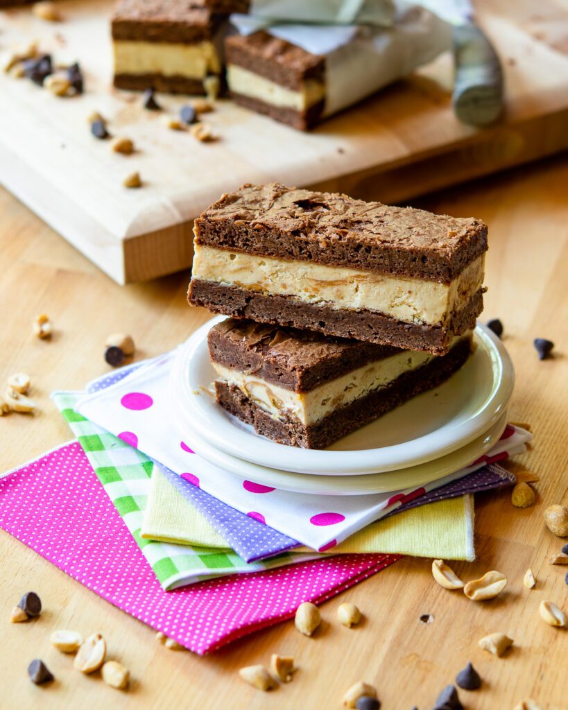 A stack of two peanut butter brownie ice cream sandwiches on a plate with colorful napkins below.