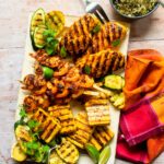 A large rectangular platter with grilled chicken, grilled shrimp and grilled tofu on it.