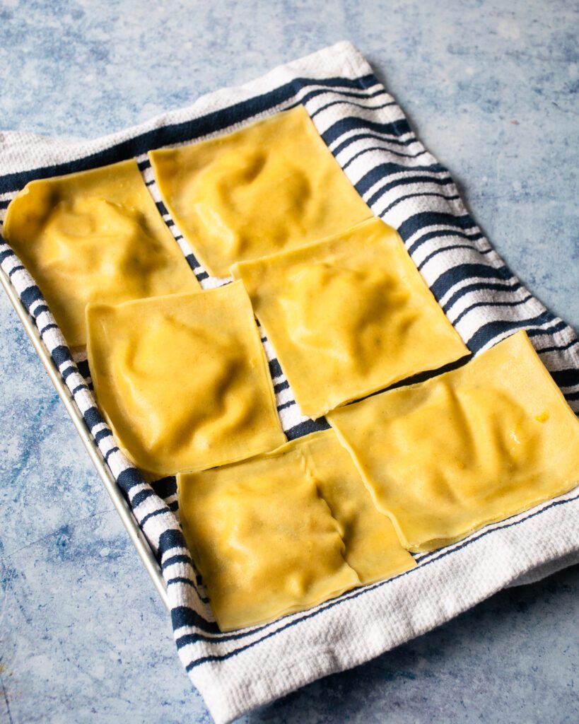 Cooked ravioli draining on a kitchen towel.