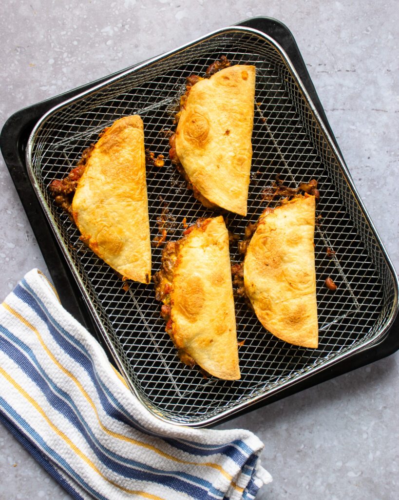 Crispy beef tacos in an air fryer basket.