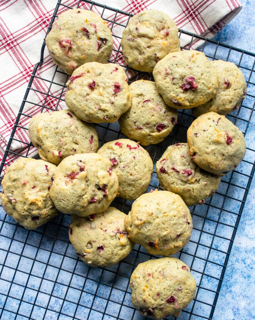 Looking down on unfrosted orange cranberry cookies on a cooling rack.