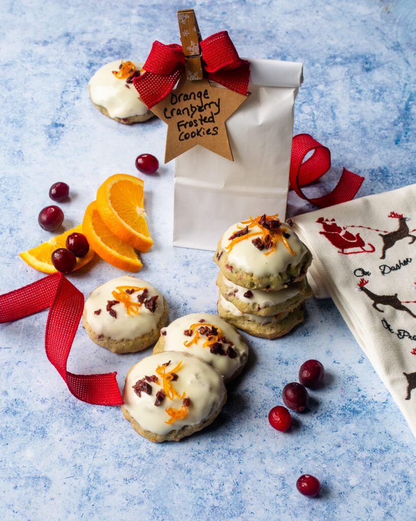 Orange cranberry frosted cookies with a gift back and ribbon.