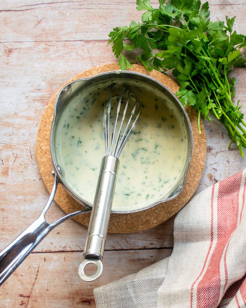 Parsley Sauce in a small saucepan with a whisk.