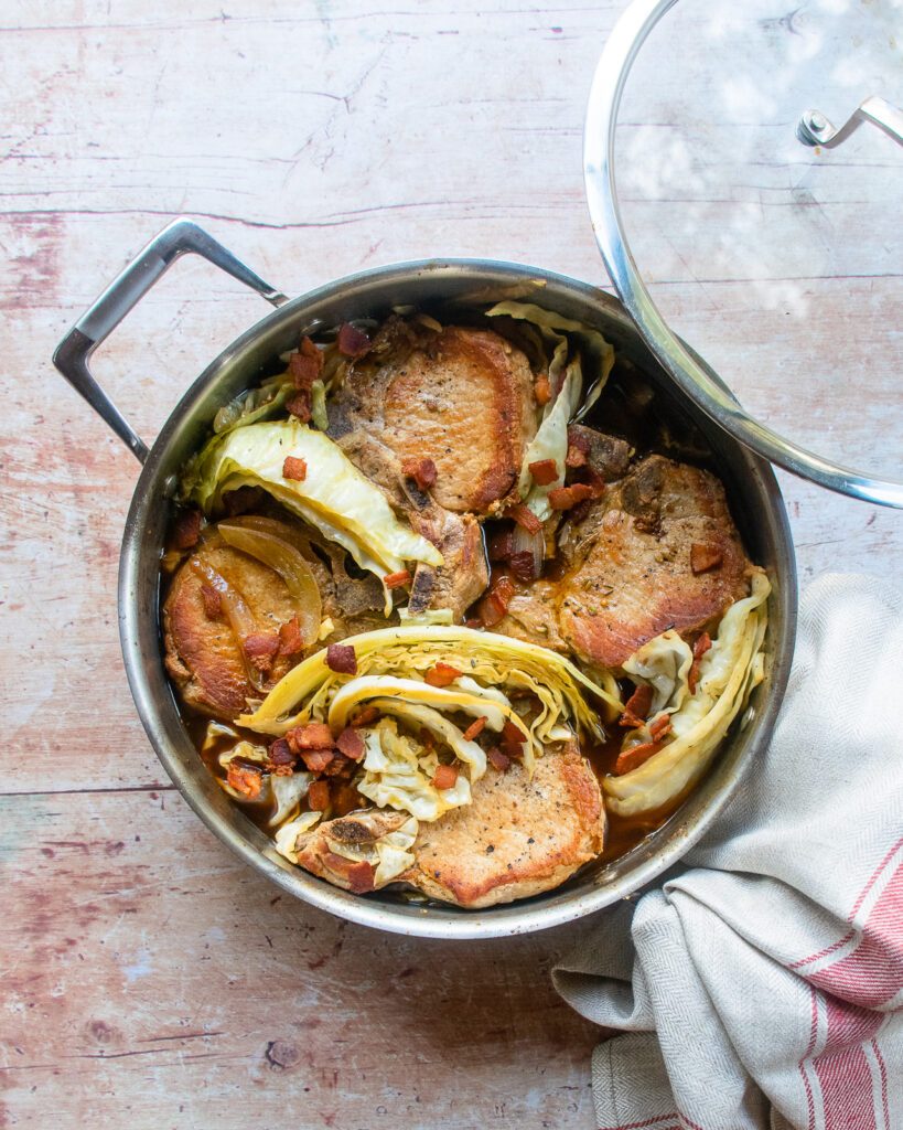 Pork chops with cabbage in a large saute pan.