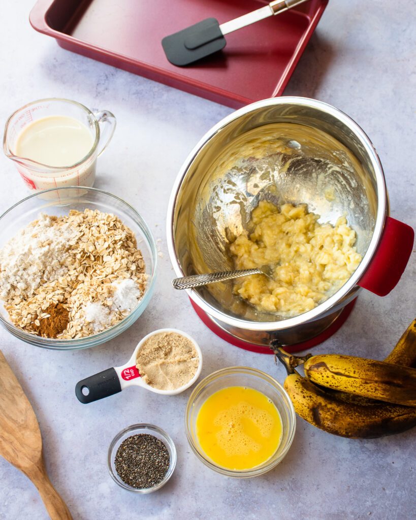 Ingredients on a table - a bowl with mashed bananas, eggs, flour, milk, chia seeds.
