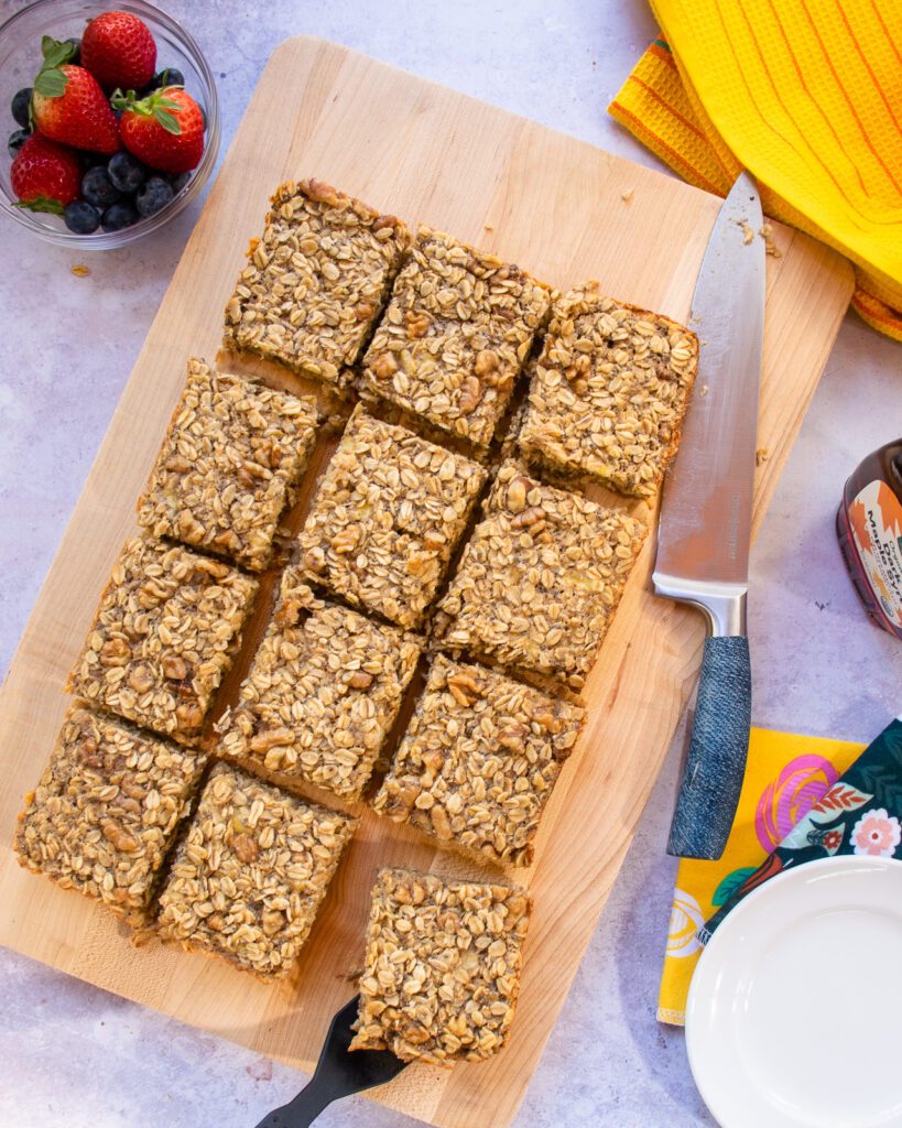 Baked banana oatmeal cut into squares on a cutting board.
