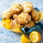 A basket of lemon streusel muffins with a blue napkin and halved lemons.