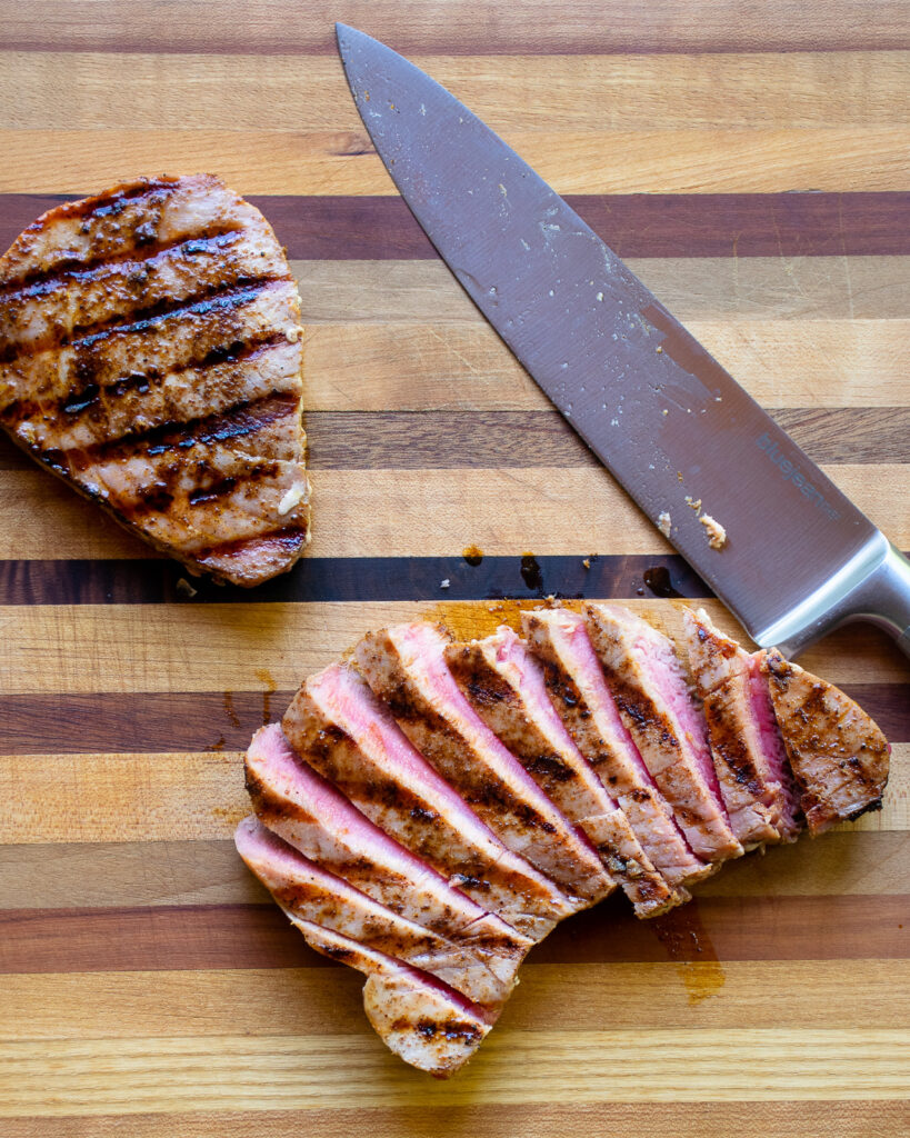 Tuna steak being sliced on a cutting board.