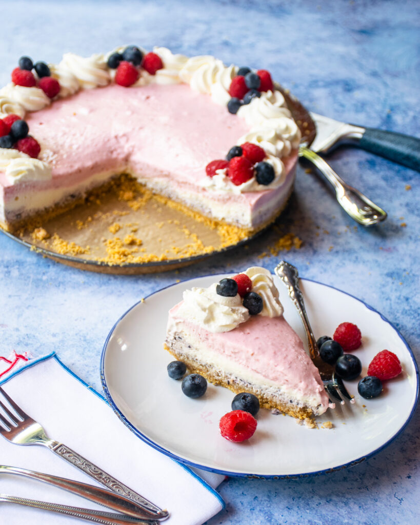 A piece of no bake cheesecake in front of the rest of the cheesecake.