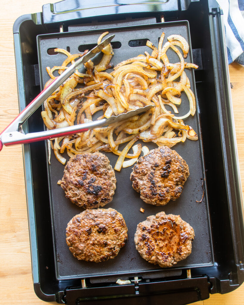 Chef cooking a hamburger patty on an electric grill or griddle