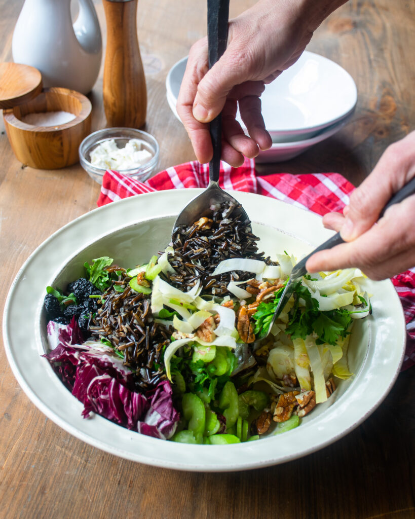 Hands tossing a wild rice salad.