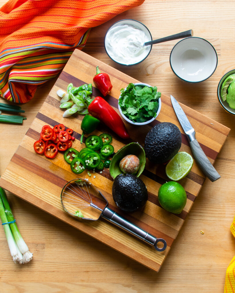 A cutting board with various ingredients chopped as garnish for enchiladas.