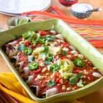 A green ceramic dish with black bean enchiladas inside.