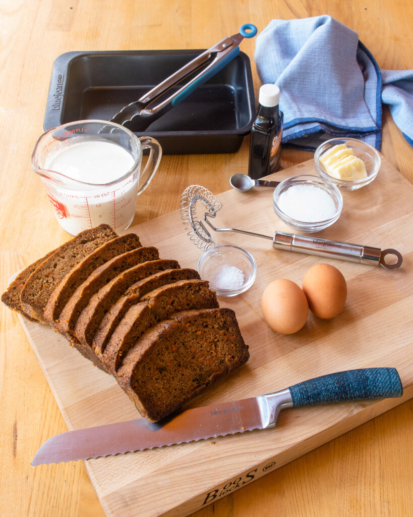 Ingredients for carrot cake french toast on a cutting board - carrot cake loaf, sliced, eggs, half and half, sugar, salt and butter.