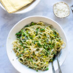 Looking down into a white bowl with creamy vegetable pasta inside.