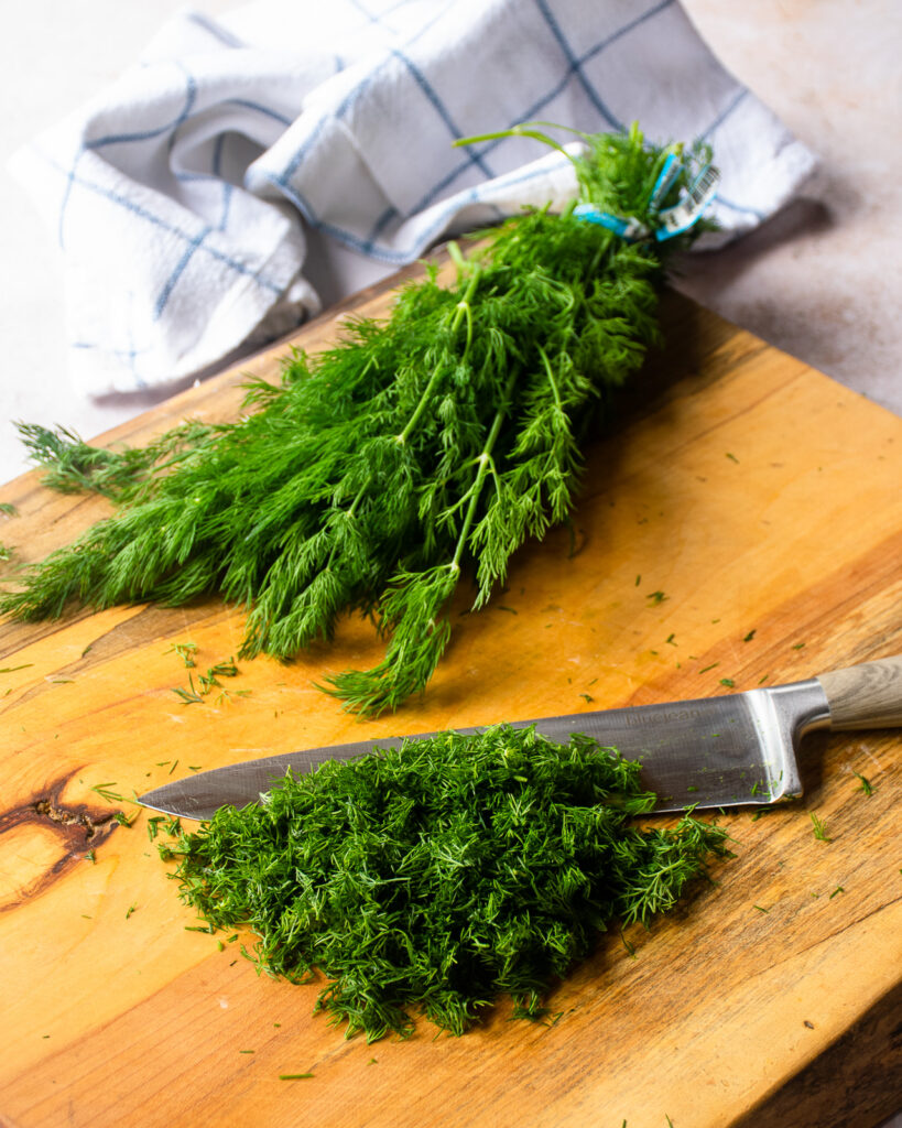 Fresh dill being chopped on a cutting board.