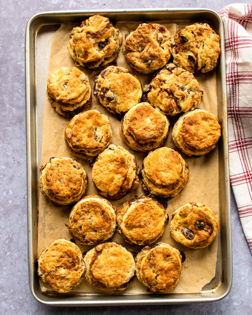 Baked cinnamon raisin biscuits on a parchment paper-lined baking sheet.