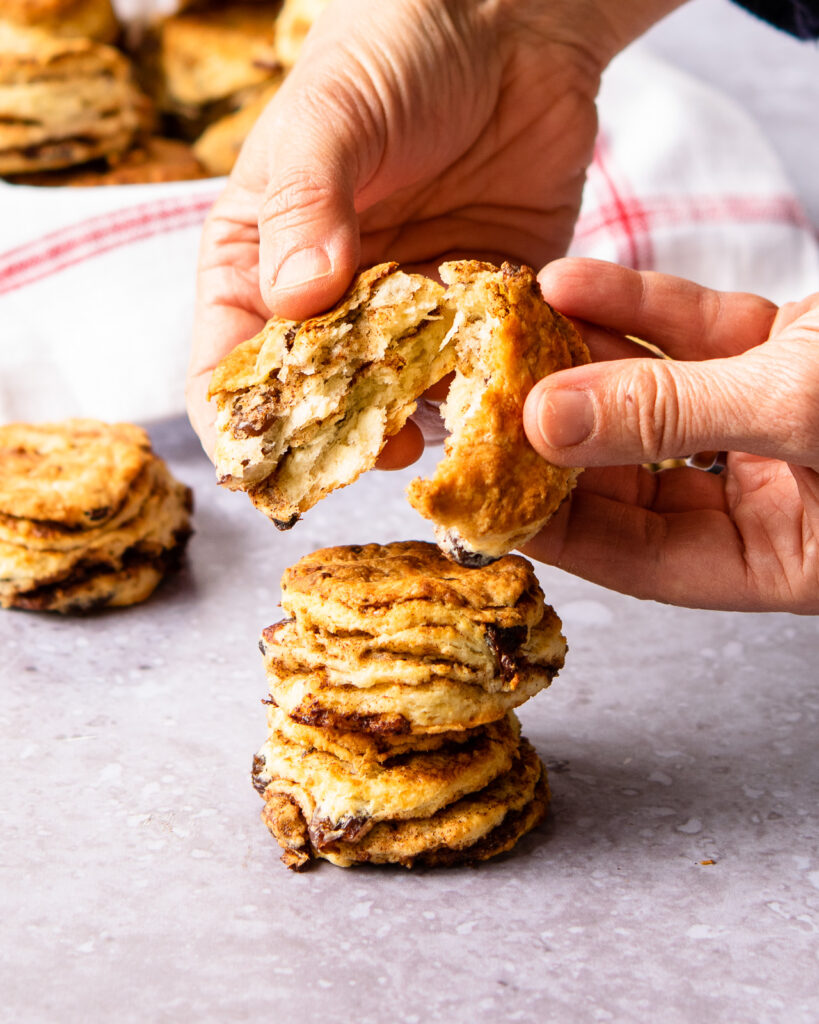 Hands breaking a cinnamon raisin biscuit open.