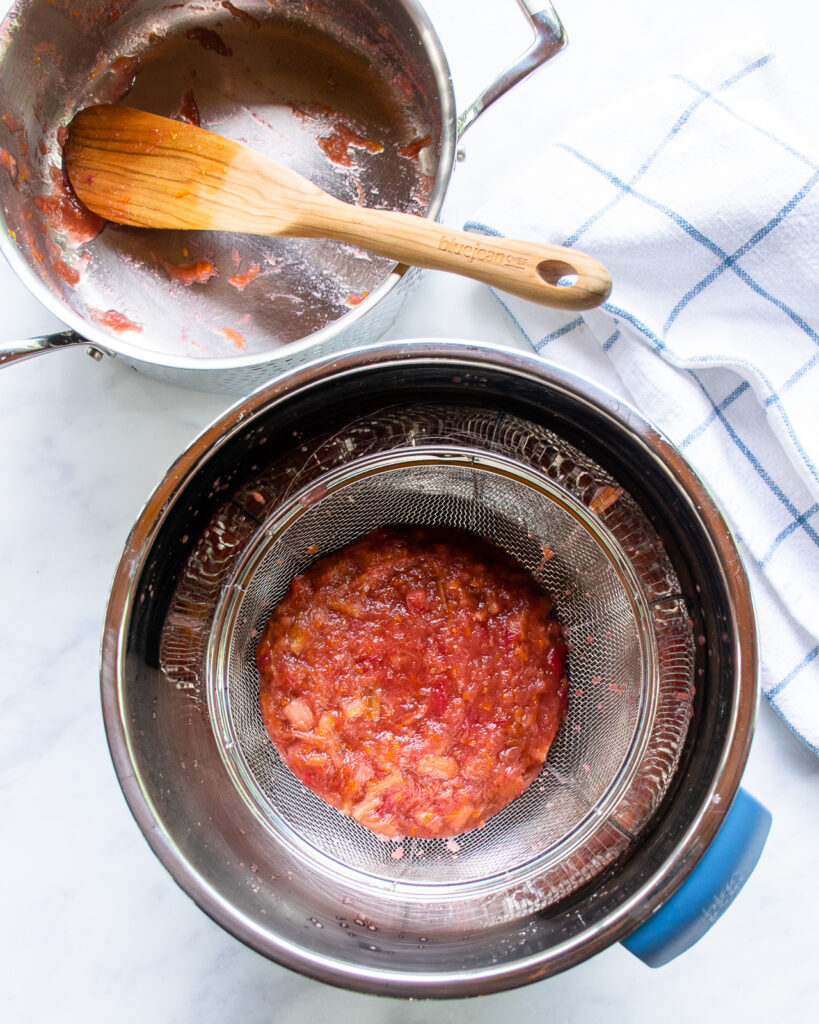 Looking down on stewed rhubarb in a strainer in a bowl. 