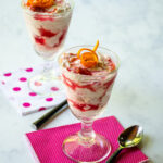 Two parfait glasses with rhubarb fool, two spoons, two pink bev naps.