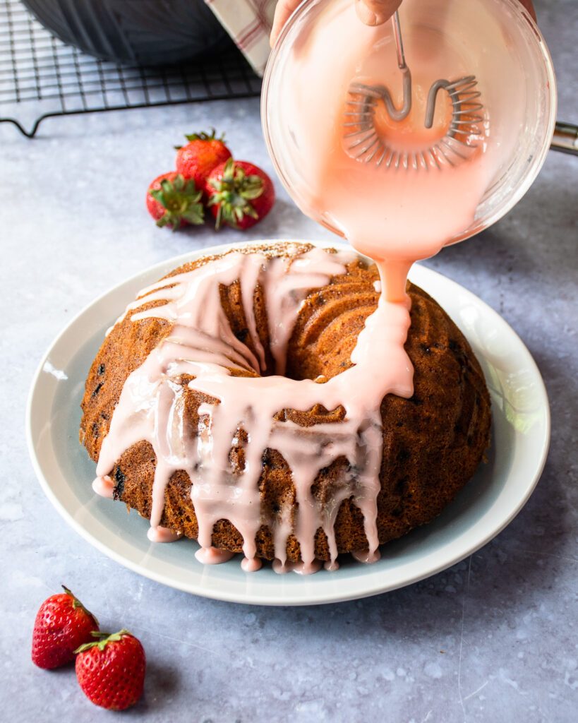 Drizzling strawberry lemon glaze over a strawberry pound cake.