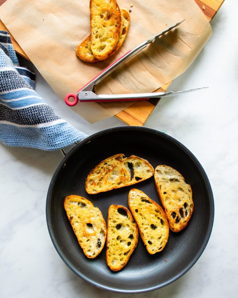 Slices of ciabatta bread frying in a skillet.