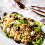 A white oval platter with pearl couscous with chicken and cherries.