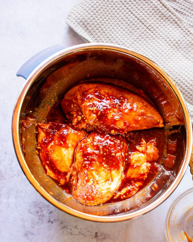 A stainless steel bowl of marinating chicken pieces.