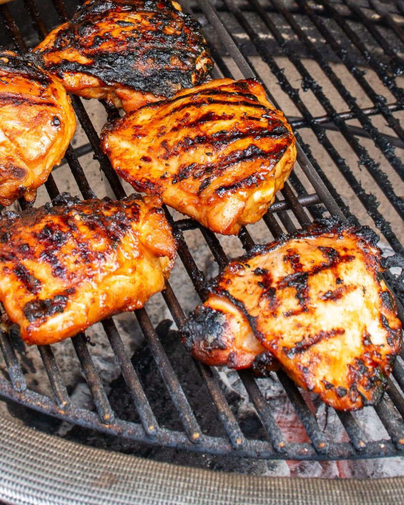 Chicken pieces on a charcoal grill.