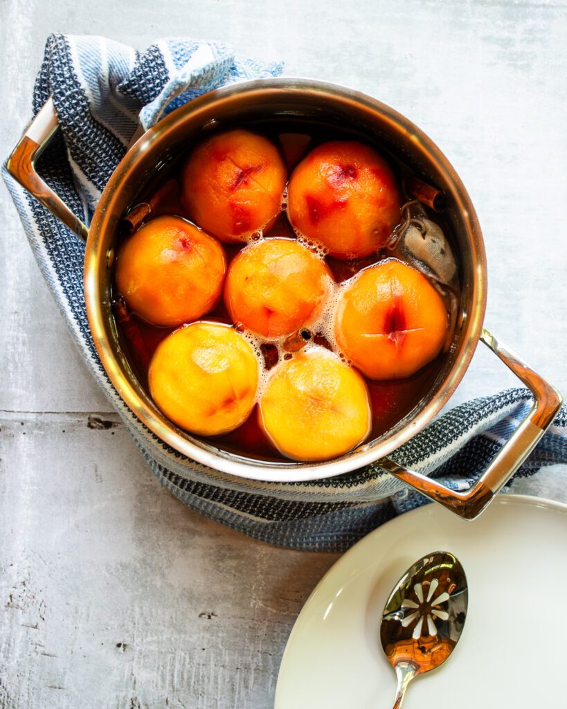 Peaches in a saucepot of pickling brine.