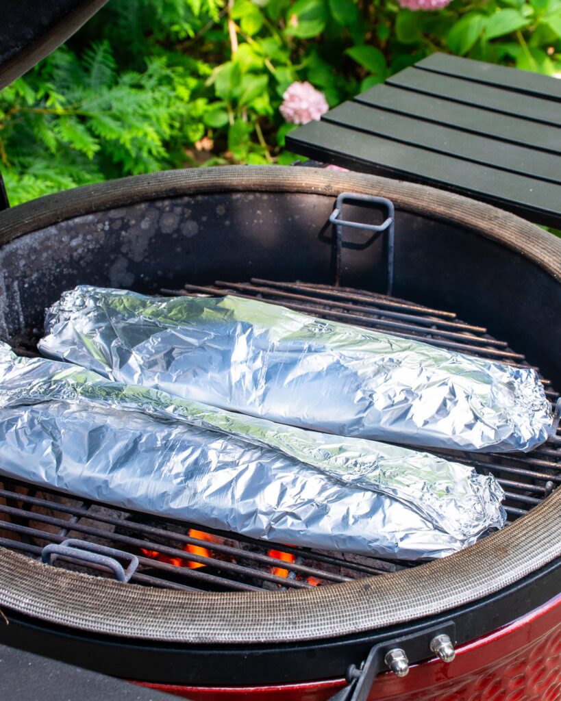 Two vegetable foil packets on a BBQ grill.