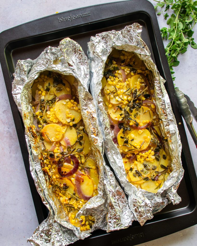 Looking down on two vegetable hobo packets on a large sheet pan.