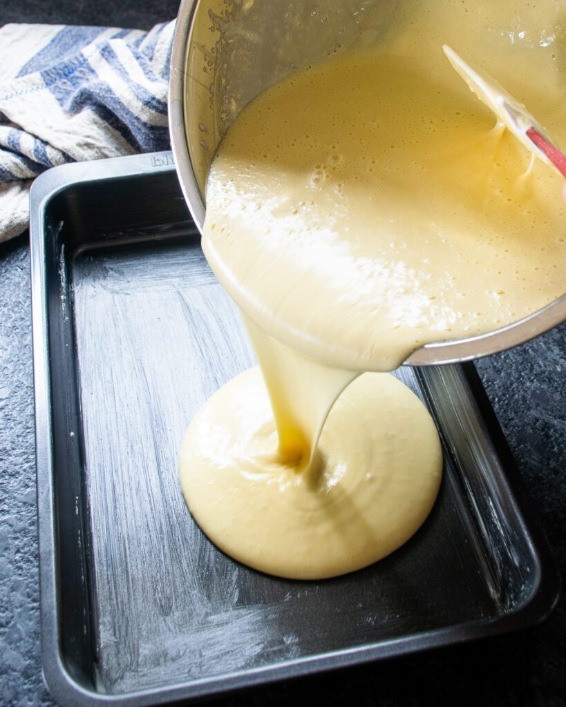 Cake batter being poured into a cake pan.