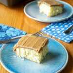 Two pieces of hot milk cake on blue plates with blue patterned napkins.