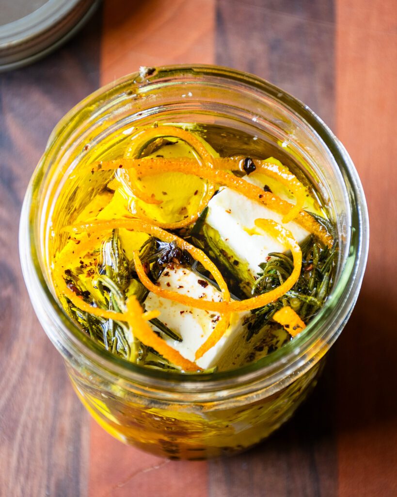 Looking down into a jar of marinated feta cheese.