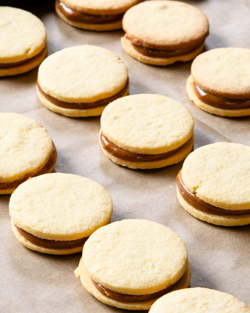 A close up of alfajores on parchment paper.